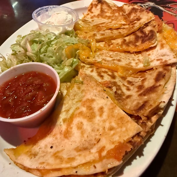 A plate of cheesy quesadillas with shredded lettuce, salsa, and sour cream at Uncle Fats Tavern.